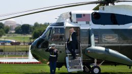 President Donald Trump waves from the steps of Marine One on the South Lawn of the White House, May 12, 2026, departing for a state visit to Beijing as a U.S. Marine renders honors with the Jefferson Memorial in the distance.